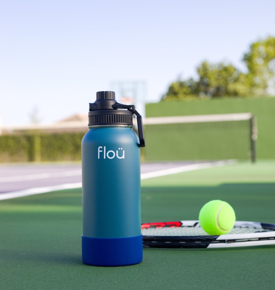 Insulated stainless steel water bottle with grip, ideal for sports on a tennis court.