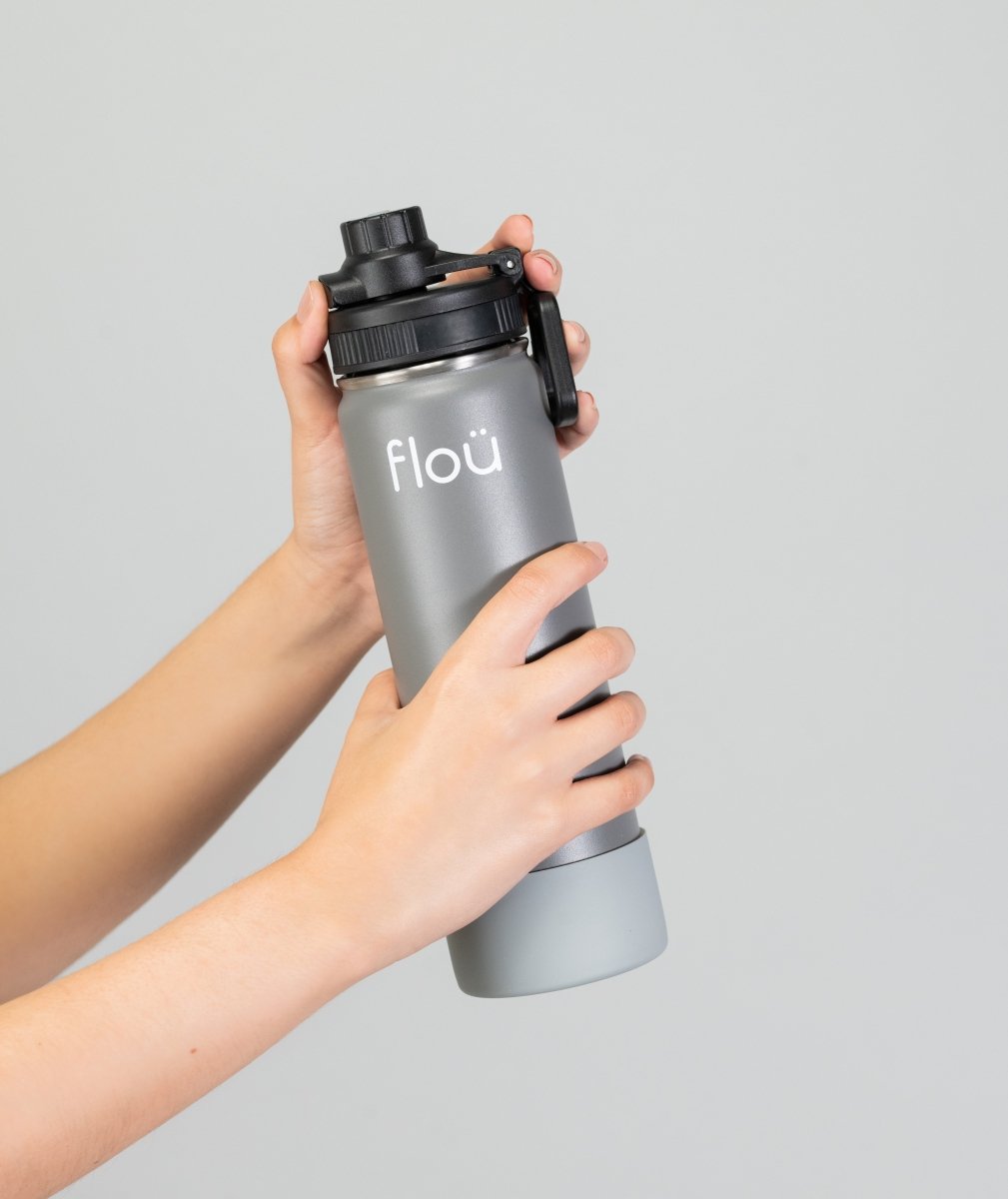 Hands holding a gray color insulated stainless steel water bottle.